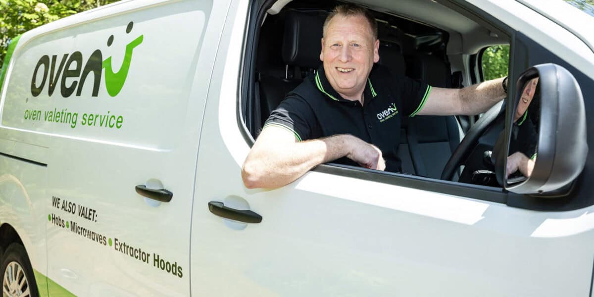 Oven valeting service vehicle with technician smiling inside.