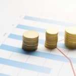 Stacked coins on financial chart showing franchise investment growth trends.